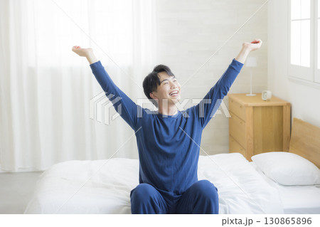 ベッドで伸びをする男性 ベッドで伸びをする男性 130865896