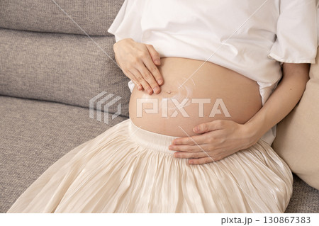 大きくなったお腹にクリームを塗る妊婦さん 大きくなったお腹にクリームを塗る妊婦さん 130867383