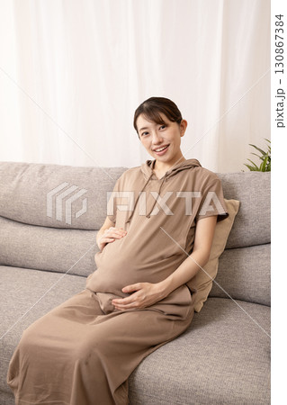 ソファーに座ってお腹をさする妊娠8ヶ月の女性 ソファーに座ってお腹をさする妊娠8ヶ月の女性 130867384