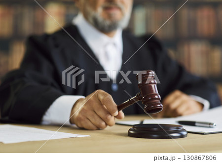 Judge striking gavel on sound block during court session, justice and law concept Judge striking gavel on sound block during court session, justice and law concept 130867806
