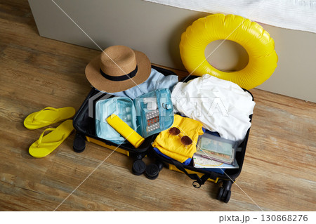 An open suitcase with clothes, cosmetics and travel accessories. An open suitcase with clothes, cosmetics and travel accessories. 130868276