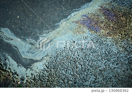 Brightly colored gasoline stain producing abstract forms on the soaked asphalt after rainfall. 130868362