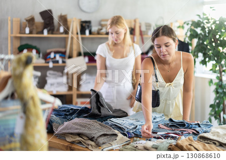 Fashionista girls near showcase examine goods, buying shorts or trousers Fashionista girls near showcase examine goods, buying shorts or trousers 130868610