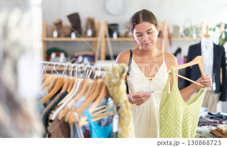Young woman choosing stylish tank tops in a clothing store 130868723