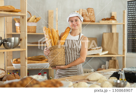 Teenage girl with basket of baguettes in bakery 130868907