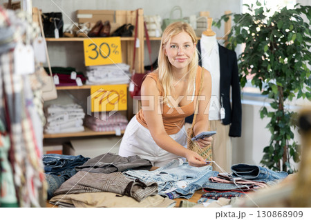 Young woman scanning qr code of jeans in clothing store 130868909