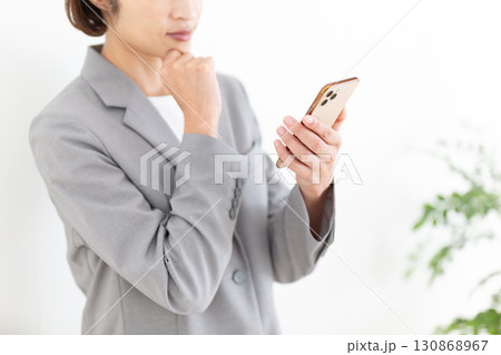 スマホを見て悩むスーツ姿のミドル女性ビジネスウーマン 130868967
