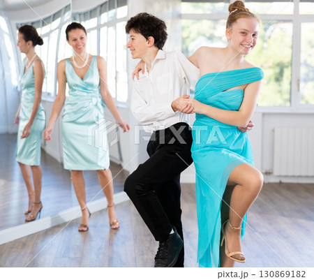 Adolescent couple practicing swing dance steps in mirrored studio Adolescent couple practicing swing dance steps in mirrored studio 130869182