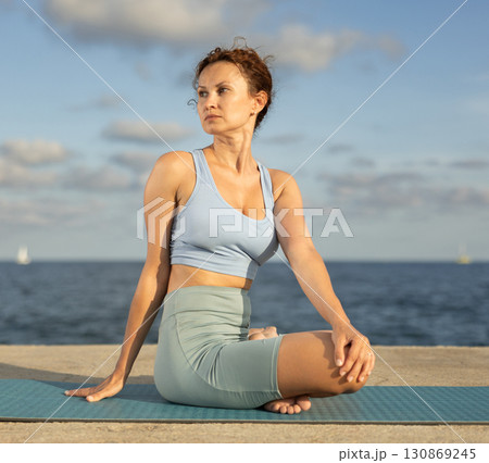 Woman performing Ardha Matsyendrasana position yoga training Woman performing Ardha Matsyendrasana position yoga training 130869245