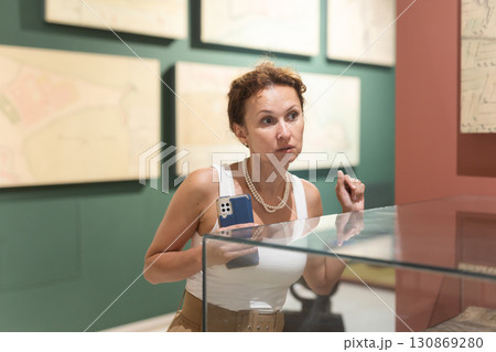 Woman observing artifacts inside glass display case at museum Woman observing artifacts inside glass display case at museum 130869280