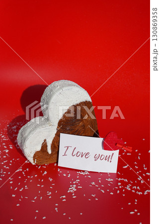 I LOVE YOU saying on paper holiday card Valentine's day celebration Heart shaped coconut flavor croissant on red background with copy space. Puff pastry new trendy sweet dessert bakery. Creamy dough 130869358