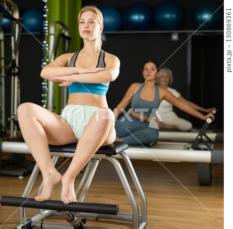 Young woman perform pilates exercises using lifes beach pilates chair Young woman perform pilates exercises using lifes beach pilates chair 130869361