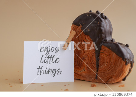 ENJOY LITTLE THINGS words on paper note Delicious fresh croissant topped with Dark chocolate flavor Ganache. Creation unique heart shape bakery. Puff pastry holiday love gift present idea Valentine's ENJOY LITTLE THINGS words on paper note Delicious fresh croissant topped with Dark chocolate flavor Ganache. Creation unique heart shape bakery. Puff pastry holiday love gift present idea Valentine's 130869374