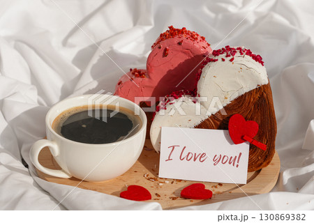 I LOVE YOU saying on greeting card Morning breakfast in bed in wooden tray Present gift idea Valentine's Day Holiday celebration Heart shaped croissants. Puff pastry new trendy sweet dessert bakery 130869382