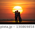 (AI生成)家族イメージ　大きな夕陽と寄り添う親子のシルエット 130869858