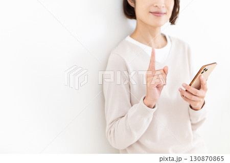スマホを持って人差し指を立てるカジュアルのミドル女性ビジネスウーマン スマホを持って人差し指を立てるカジュアルのミドル女性ビジネスウーマン 130870865