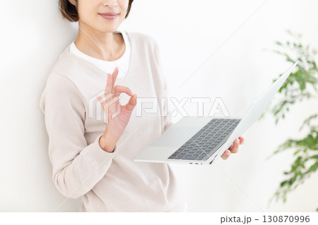 パソコンを持って丸サインをするカジュアルのミドル女性ビジネスウーマン 130870996