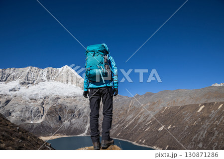 Backpacking woman hiking on high altitude mountain top 130871286