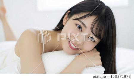 枕を抱きしめて幸せそうに微笑むキャミソール姿の女性 130871978