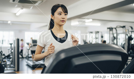 ランニングマシーンで走る若い女性 130872010
