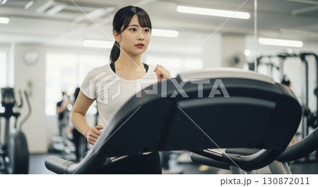 ランニングマシーンで走る若い女性 130872011
