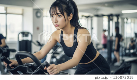 エアロバイクを漕ぐ若い女性 エアロバイクを漕ぐ若い女性 130872019