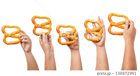 Collection set of human hands holding a salty baked brown pretzel isolated over a white background. Oktoberfest festival Collection set of human hands holding a salty baked brown pretzel isolated over a white background. Oktoberfest festival 130872991
