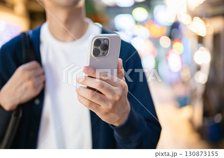 夜の街でスマホを操作する男性 130873155