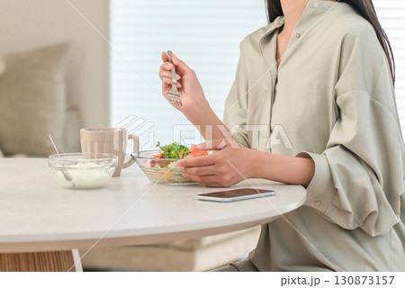 朝食にサラダとヨーグルトを食べるダイエット中の若いアジア人女性 朝食にサラダとヨーグルトを食べるダイエット中の若いアジア人女性 130873157
