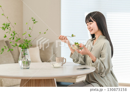 朝食にサラダとヨーグルトを食べるダイエット中の若いアジア人女性 朝食にサラダとヨーグルトを食べるダイエット中の若いアジア人女性 130873158