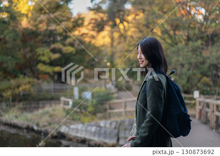 秋の公園で紅葉を眺める女性 130873692