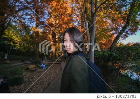 秋の公園を散歩する女性のポートレート 130873703