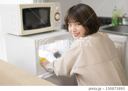 冷蔵庫から飲み物を取り出す若い女性 冷蔵庫から飲み物を取り出す若い女性 130873893