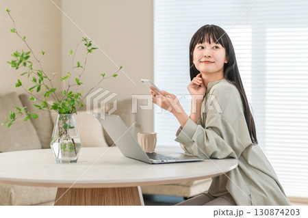 家でスマホ,スマートフォンを使って仕事する若いアジア人女性 130874203