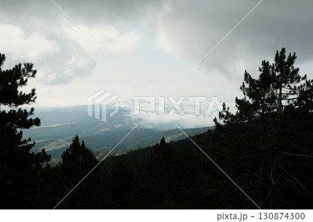 Misty mountain view from Divcibare, Serbia. Clouds rolling over dark forested hills create a dramatic and peaceful scene Misty mountain view from Divcibare, Serbia. Clouds rolling over dark forested hills create a dramatic and peaceful scene 130874300