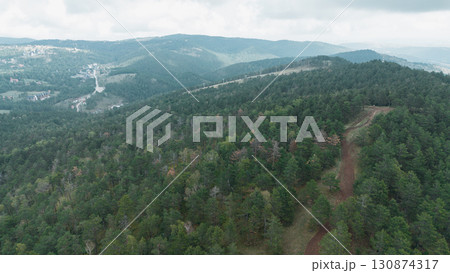 Aerial view of a forest trail winding through the green hills and ski slopes at the distance. Divcibare, Serbia Aerial view of a forest trail winding through the green hills and ski slopes at the distance. Divcibare, Serbia 130874317