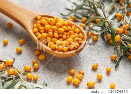 Wooden spoon overflowing with fresh sea buckthorn berries and leaves 130874389