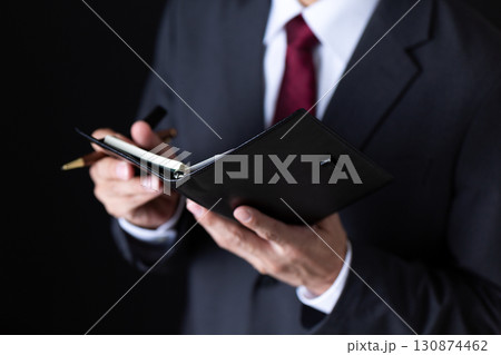 手帳を見るスーツを着たミドル男性ビジネスマン 手帳を見るスーツを着たミドル男性ビジネスマン 130874462