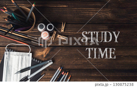 A wooden table with a bowl of pencils, a bottle, and a pair of scissors A wooden table with a bowl of pencils, a bottle, and a pair of scissors 130875238