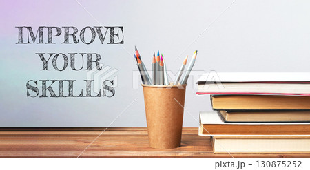 A wooden desk with a cup of pencils and a stack of books 130875252