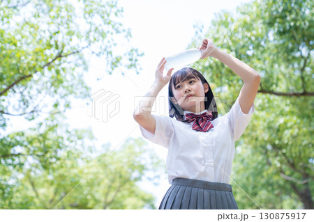 ペットボトルを額に当てる女子高生 130875917