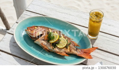 Grilled red snapper with lemon served with passion fruit juice on a white table at the beach Grilled red snapper with lemon served with passion fruit juice on a white table at the beach 130876030