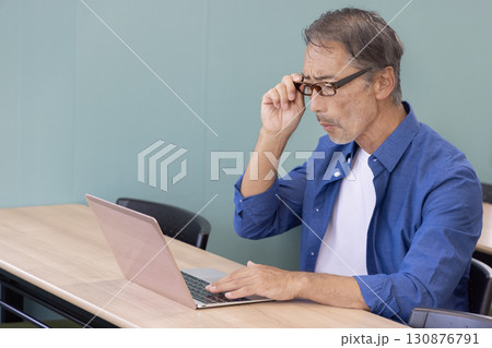 パソコンを使う老眼のシニア男性 130876791