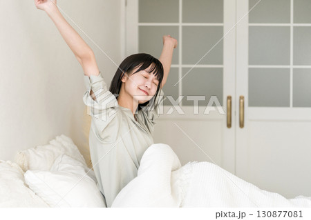 朝ベッドルームで熟睡,快眠できて笑顔でストレッチする女性 朝ベッドルームで熟睡,快眠できて笑顔でストレッチする女性 130877081