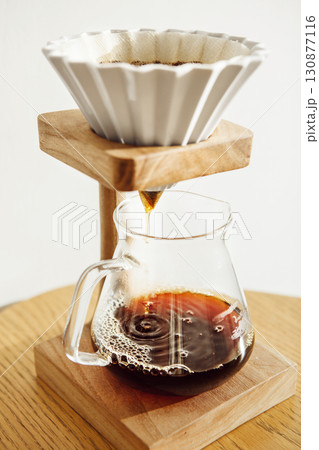 Brewing Coffee With an Origami Pour Over Setup on Wooden Table in Cozy Kitchen Setting Brewing Coffee With an Origami Pour Over Setup on Wooden Table in Cozy Kitchen Setting 130877116