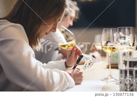Female sommelier examination to get certificate professional work of winemaking. Sommelier degustate wine. 130877138