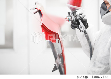 Close-up, hand of repairman painting car body elements in the paint chamber. 130877148