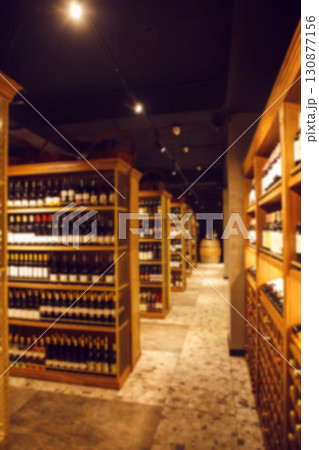 Vertical wide-angle interior shot of big cellar in wine shop with wooden shelves for alcohol drinks. Long corridor of wine collection in elite alcoholic beverages. 130877156