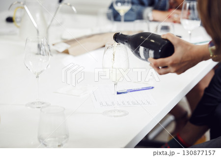 Close-up of sommelier pouring white sparkling wine into wine glass. Training and wine tasting. Close-up of sommelier pouring white sparkling wine into wine glass. Training and wine tasting. 130877157