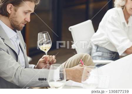 sommelier tasting white wine and making notes to degustation card during wine expert training. sommelier tasting white wine and making notes to degustation card during wine expert training. 130877159